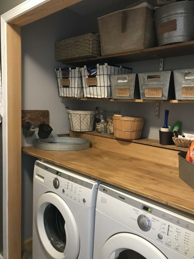 a washer and dryer in a small room with shelves on the wall above them