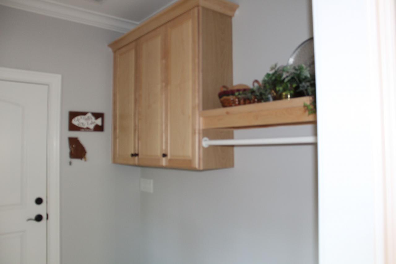 The laundry room has natural maple a shelf and a hanging bar
