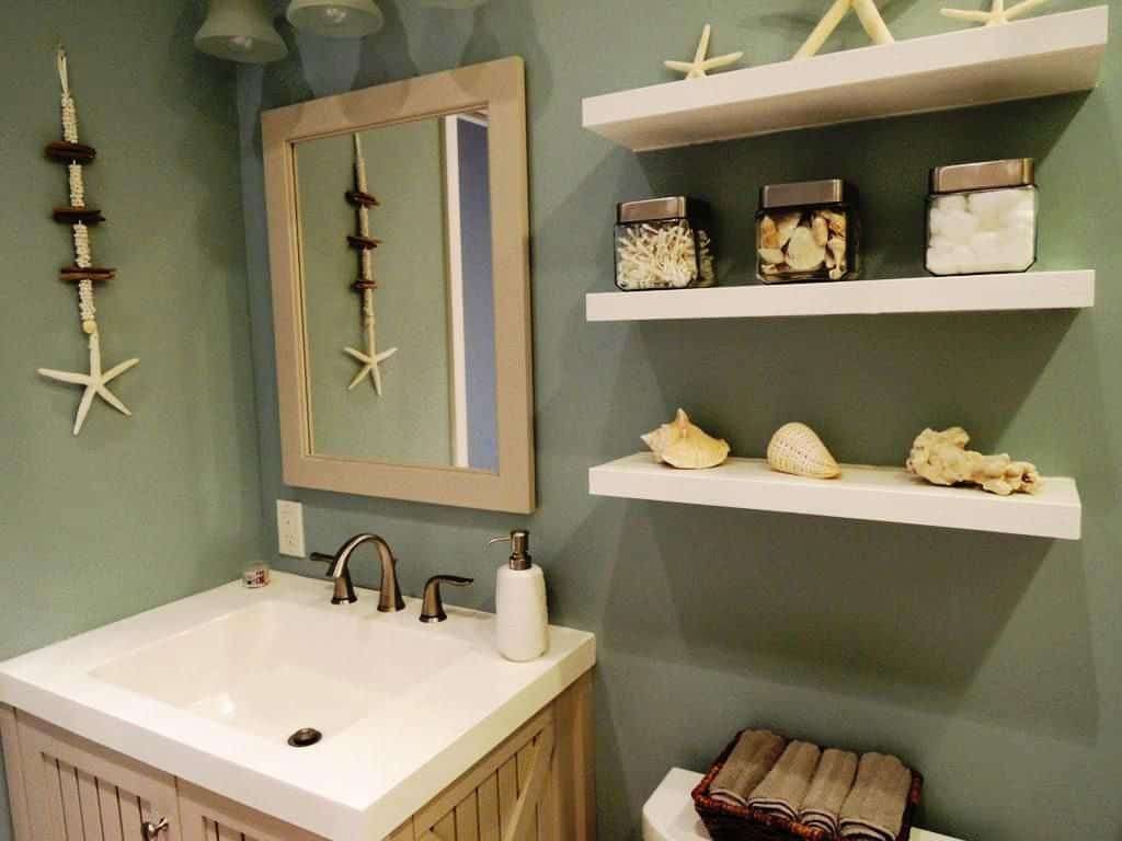Beach themed bathroom with seashell accessories and floating shelves