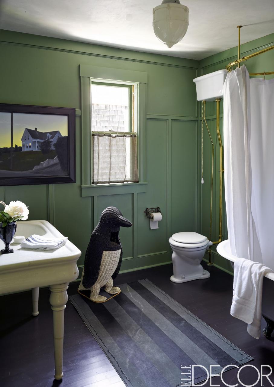 a bathroom with green walls and a white sink sitting under a mirror